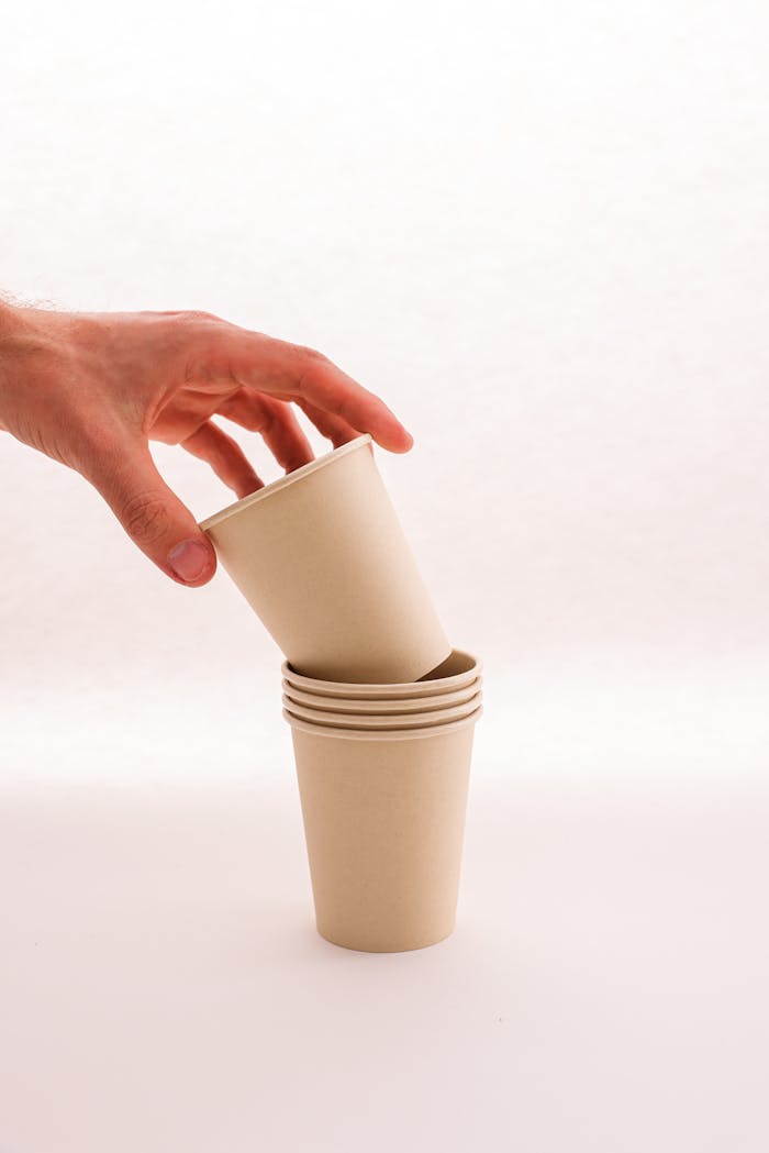 Close-up of hand stacking biodegradable paper cups, emphasizing sustainability.